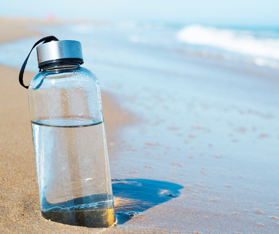 A glass water bottle on a beach