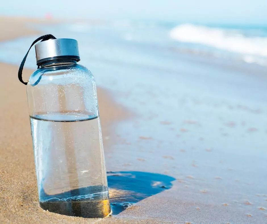 A glass water bottle on a beach